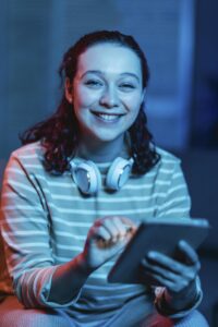 vista-frontal-de-la-mujer-sonriente-en-casa-con-auriculares-y-tableta